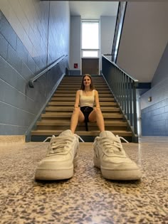 a woman sitting on the floor in front of some stairs with her feet propped up