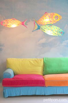 a colorful couch sitting in front of a wall with two fish hanging from it's sides