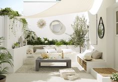 an outdoor living area with white furniture and plants