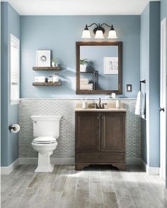 a white toilet sitting next to a wooden sink vanity in a bathroom under a mirror