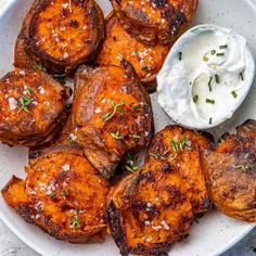 a white plate topped with potatoes covered in sour cream and garnished with herbs