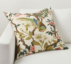 a white couch with a floral pillow on it's back and the pillows are made out of fabric