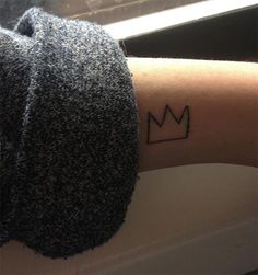 a woman's arm with a small crown tattoo on the left side of her arm