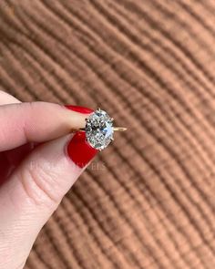 a woman's hand holding an engagement ring with a diamond on the middle finger