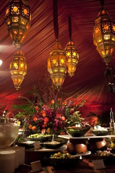 a table topped with lots of food under hanging lights