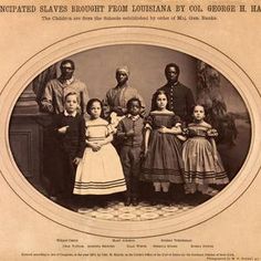 an old black and white photo of several children in front of a man with his arm around a woman