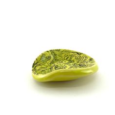 a yellow and green leaf shaped dish on a white surface, with an intricate design