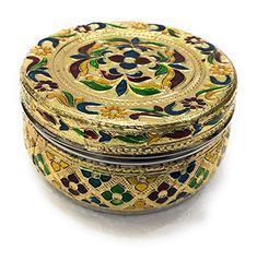 an ornately decorated metal box sitting on top of a white surface with gold trim