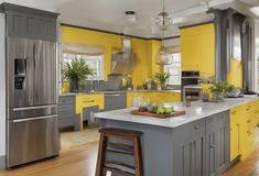 a kitchen with yellow and gray cabinets, stainless steel appliances and wooden floors is shown