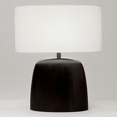 a black table lamp with a white shade on the base and a light in the middle