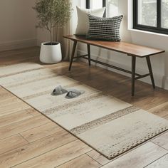 a wooden bench sitting on top of a hard wood floor next to a white rug