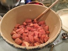 a bowl full of diced meat with two wooden spoons resting on the side