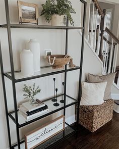 a shelf with books and plants on it in the corner of a room next to stairs