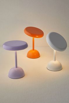 three different colored stools sitting next to each other on a white surface with no one around them