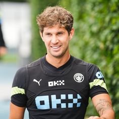 a man with tattoos on his arm wearing a black shirt and smiling at the camera