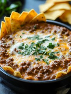 a close up of a bowl of food with tortilla chips on the side