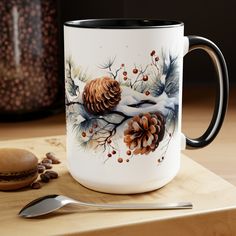 a white and black coffee mug sitting on top of a wooden table next to a spoon