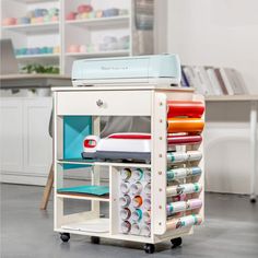 a cart with many different types of crafting supplies on it in a room next to a desk