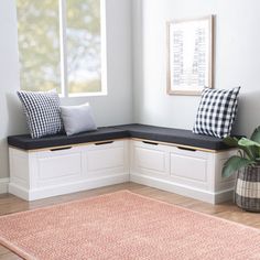 a corner bench with pillows on it next to a potted plant and window sill