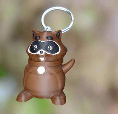 a brown toy with a racoon on it's face is hanging from a key chain