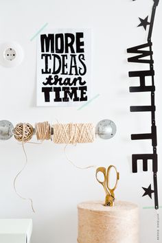 a white wall with some black and white art on it's walls, scissors and twine