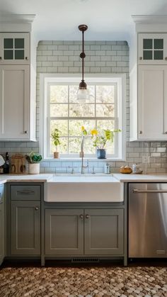 a kitchen with white cabinets and gray counter tops, an open window above the sink