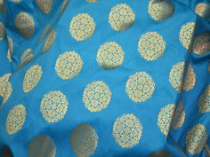 Turquoise Brocade by the Yard Fabric Wedding Dresses Banarasi Fabric Banaras Blended silk Brocade costume fabric lehenga Skrit Fabric. This is a beautiful banarasi blended silk brocade mandala design fabric in Turquoise Blue and Gold. ➤Product: Brocade Fabric ➤Fabric Type: Blended Silk (Viscose and Silk) Fine quality Zari Brocade Weaving from Banaras ➤Color: Turquoise Blue and Gold ➤Width: 44 inches. ➤Condition: New ➤Code: bg491 ➤Listing for 1 Yard of fabric. ➤Care: Dry Clean Only You can use th Blue Jamawar Anarkali Set For Wedding, Blue Motif Anarkali Set For Wedding, Festive Blue Anarkali Set In Jamawar, Blue Anarkali Set With Motifs For Wedding, Blue Jamawar Anarkali Set For Festivals, Festive Blue Jamawar Anarkali Set, Traditional Turquoise Choli With Zari Work, Blue Choli With Traditional Patterns For Festivals, Bollywood Style Blue Jamawar Anarkali Set