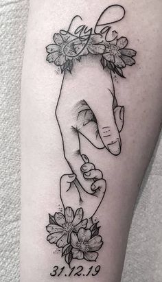 a black and white photo of a hand holding a baby's hand with flowers on it