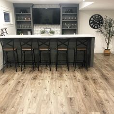 an image of a kitchen setting with wood flooring and bar stools in it