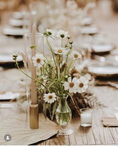 the table is set with white flowers in vases and place settings for guests to sit at