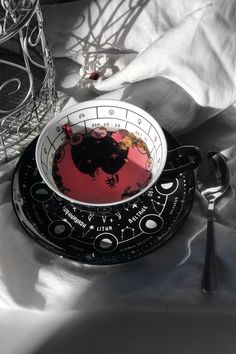 a black and white plate with a red bowl on it next to a glass vase