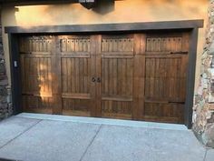 two wooden garage doors in front of a stone building