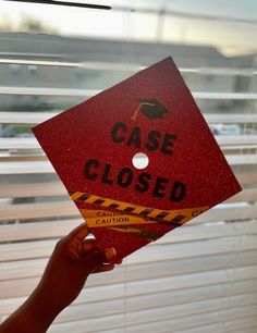 a hand holding up a red sign that says case closed with caution tape on it