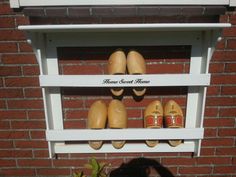 there are several pairs of shoes on the shelf in front of a brick wall that says home sweet home