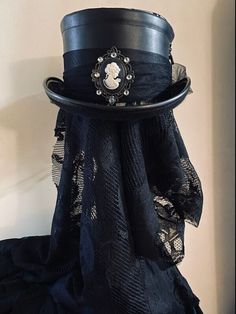 Black felt, top hat style covered black floral lace. Black faux leather band that laces up and ties on the side. Black tulle wraps around the faux leather band and ties into a big bow in the back. The hat is turned up on the sides and is finished with a beautiful black and white gothic cameo trimmed in rhinestone like jewels, The hat inside is black felt. on top it appears to be a silvery white with  the black floral lace over. This hat has a very Victorian look. Gorgeous piece and it reminds me Victorian Headpiece, Victorian Gothic Style, Gothic Tops, Gorgeous Blouses, Black Bow Tie, Tulle Bows, Black Tulle, Black Felt