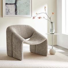 a chair sitting on top of a rug next to a vase with flowers in it