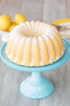 a bundt cake on a blue plate with lemons in the background