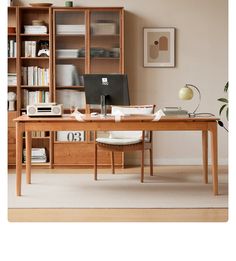 a desk with a computer and bookshelf in the background, next to a chair