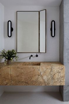 a bathroom with marble counter top and two mirrors on the wall above it, along with a potted plant