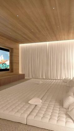 a large bed sitting under a flat screen tv in a bedroom next to a window