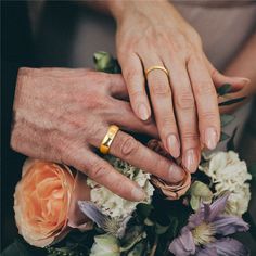 two people holding hands over a bouquet of flowers