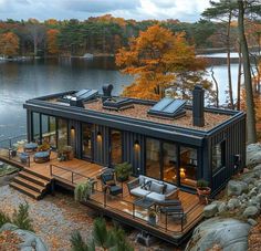 a house built into the side of a lake surrounded by rocks and trees in autumn