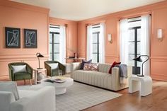 a living room filled with lots of furniture next to tall windows and wooden flooring