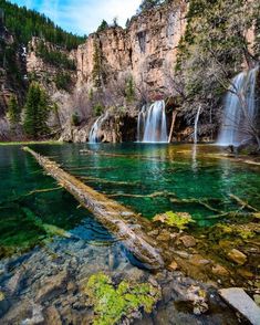 the water is crystal green and there are some rocks in front of it with moss growing on them