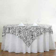 a table with silver sequins on it and two wine glasses next to it