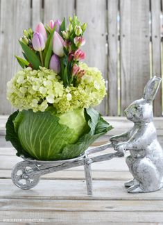 a metal rabbit pulling a wheelbarrow filled with flowers