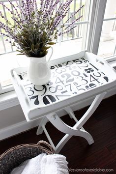 a white table topped with a vase filled with purple flowers