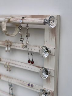 a white wooden rack with lots of jewelry hanging on it