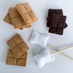 four knitted squares and two knitting needles on a white surface