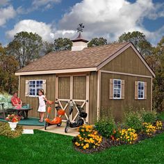 two people are sitting on a bench in front of a small shed with a bicycle